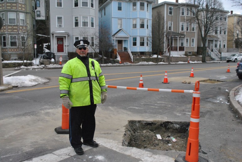 Police Officer William Jones works a detail as test pits are dug Monday, Feb. 24 in the Hyde Square area.